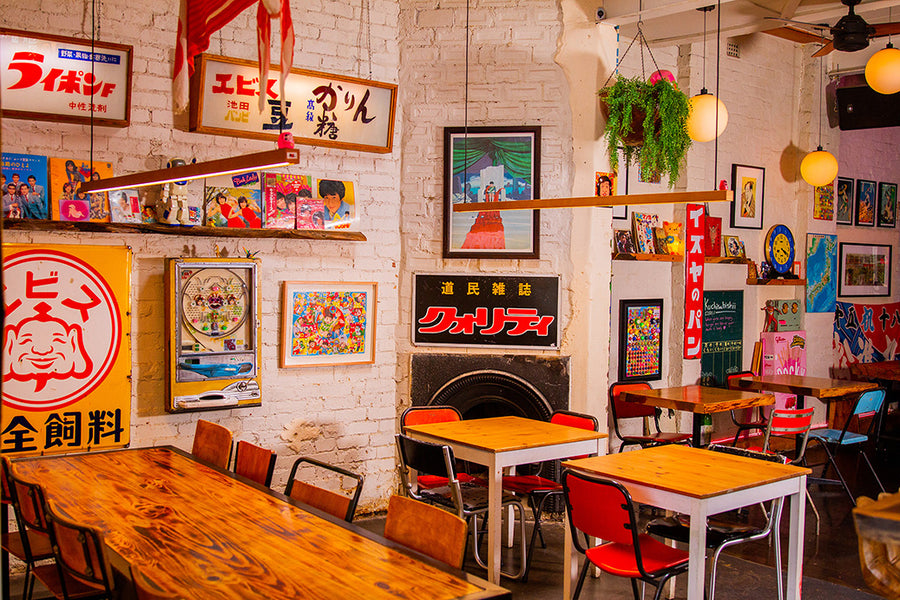 The cozy, retro-style  interior of Chotto Motto with wooden tables, red and black chairs. The walls covered in Showa Era Japanese vintage items.