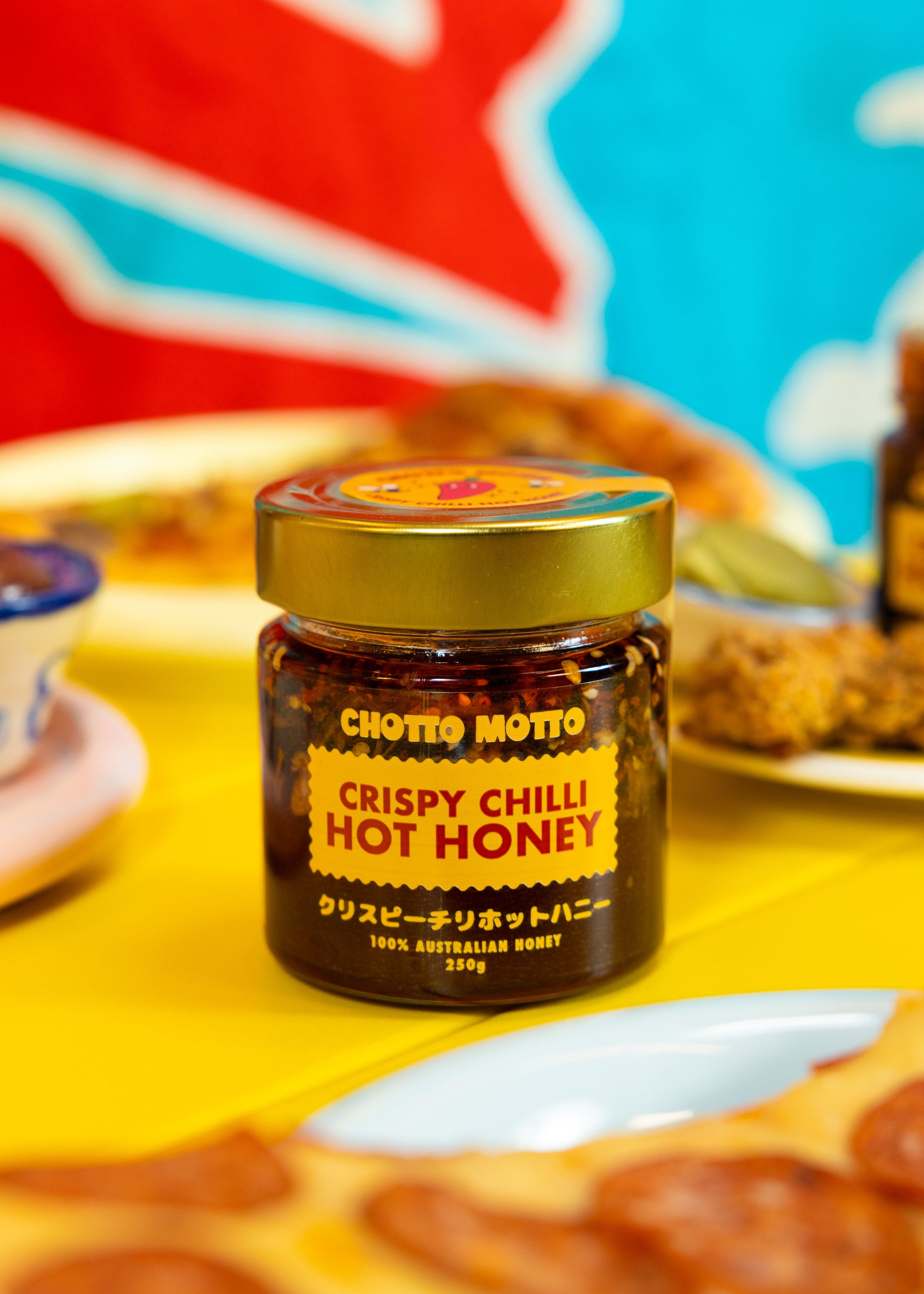 Jar of Chotio Motto Crispy Chilli Hot Honey on a colorful background